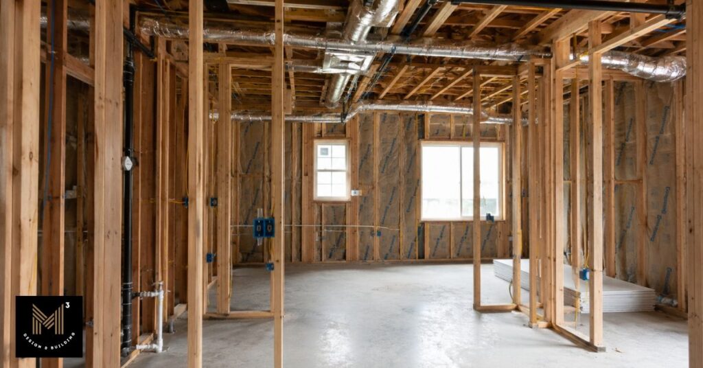 Unfinished garage interior showing framing, insulation, utility rough-ins, and HVAC installation during construction of a residential ADU conversion.